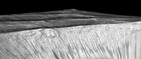 Dark narrow streaks, called "recurring slope lineae," emanate from the walls of Garni Crater on Mars, in this view constructed from observations by the High Resolution Imaging Science Experiment (HiRISE) camera on NASA's Mars Reconnaissance Orbiter. Image and caption by NASA's Jet Propulsion Laboratory.